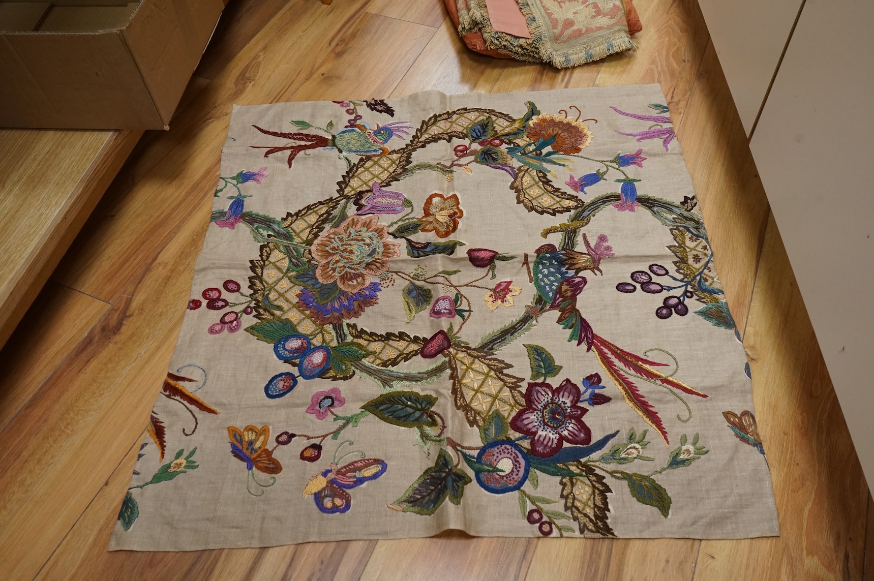 An Arts and Crafts embroidered table cover, an embroidered printed fabric sample later embroidered and a bird embroidered cushion.